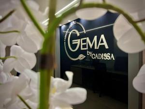 Apartamentos Gema by Cadissa في ميديلين: مجموعة من الزهور البيضاء أمام لافتة