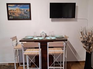 mesa de comedor con sillas y TV en Rhodian Wavespot en Ialyssos