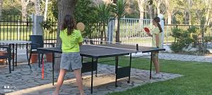 dos chicas jugando ping pong en una mesa de ping pong en Philoxenia Apartments, en Kryonéri