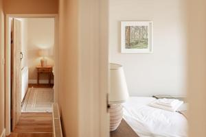 a white bedroom with a bed and a lamp at The Barn in Longhope - Luxury Barn Conversion in Longhope