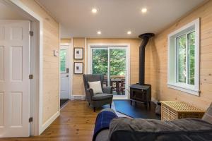 a living room with a stove and a couch and a chair at Oasis de paix sous les arbres, avec accès au quai, à 1h de Montréal in Saint-Calixte