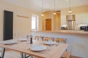 The Barn in Longhope - Luxury Barn Conversion في Longhope: طاولة خشبية عليها صحون واكواب في مطبخ
