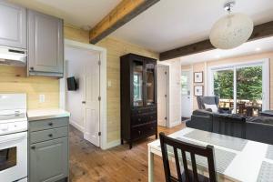 a kitchen and living room with a table and a couch at Oasis de paix sous les arbres, avec accès au quai, à 1h de Montréal in Saint-Calixte