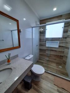a bathroom with a toilet and a glass shower at Carpe diem Beach House - Jardim Peró - Cabo Frio RJ in Cabo Frio