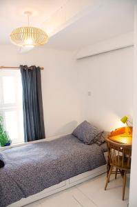 a bedroom with a bed and a desk and a window at Lovely cottage with private garden in Penryn