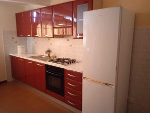 フォルツァ・ダグロにあるCASA DI NONNAのキッチン(赤いキャビネット、白い冷蔵庫付)