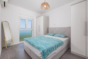 a white bedroom with a bed and a mirror at Apartment Kvarner View in Kostrena