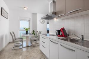 a kitchen with white cabinets and a sink and a table at Apartment Kvarner View in Kostrena