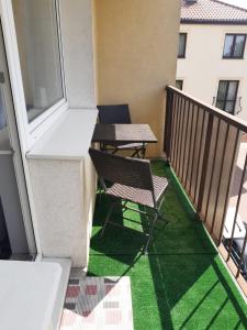 two chairs and a table on a balcony with green grass at Słoneczny pokój z balkonem. in Gdańsk