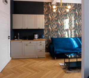 een woonkamer met een blauwe bank en een keuken bij Apartament Zwycięzców 2 in Stargard