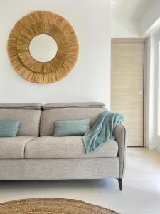 ein Wohnzimmer mit einer Couch und einem Spiegel in der Unterkunft Le Soleil d’or in Théoule-sur-Mer