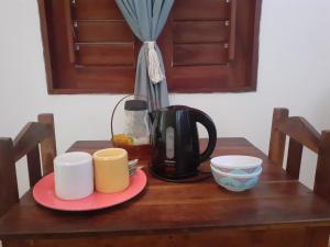 a table with a coffee pot and cups on it at Chalés Bons Ventos - Icaraizinho in Icaraí