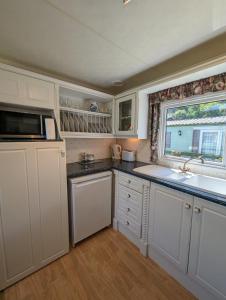 a kitchen with white cabinets and a sink and a window at The Lambourne in Dunoon