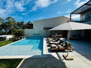 a swimming pool with lounge chairs and an umbrella at Luxury Stone Houses Corfu in Píthos