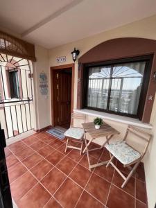 weranda z 2 krzesłami, stołem i oknem w obiekcie Casa Nico w mieście Torrevieja