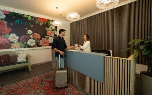 a man and a woman standing at a counter with their luggage at Nice Hotel Bibione in Bibione