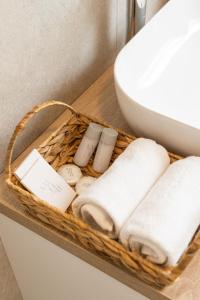 una cesta de toallas y artículos de aseo en un estante junto a un fregadero en Rooms & Apartment Perak, en Kutjevo