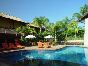 una piscina con sillas y sombrillas junto a un complejo en Ilhaflat ilhabela -Apartamento Schiavetti, en Ilhabela