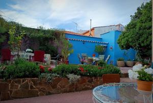 een tuin met een tafel en stoelen en een blauwe muur bij 25 de Abril in Santa Cruz de la Sierra