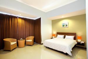 een hotelkamer met een bed en twee stoelen bij The Studio Inn Nusa Dua in Nusa Dua