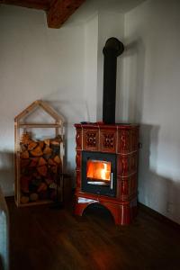 a wood stove in a room with a pile of logs at Švajkova chyža in Šumiac