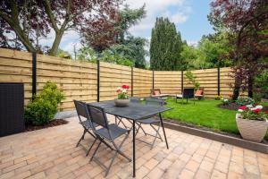 a patio with a table and chairs and a fence at Idéal Famille: Jardin, Proche Commerces & Plage in Bray-Dunes
