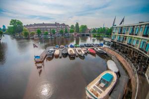 eine Gruppe von Booten, die in einem Yachthafen auf einem Fluss geparkt sind in der Unterkunft Apollo Hotel Amsterdam, a Tribute Portfolio Hotel in Amsterdam