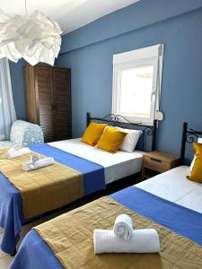 2 camas en una habitación con paredes azules en La Scala family apartments, en Nea Roda