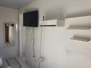 Una sala de estar con un televisor en la pared. en Kitnets Aconchegantes Próximo ao Shopping, en Curitiba