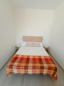 Un dormitorio con una cama con una manta a cuadros. en Sunshine, What else?, en Las Palmas de Gran Canaria
