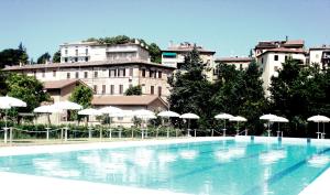 a large swimming pool in front of a building with umbrellas at Il Barchio loft in un palazzo di fine 800 a Jesi in Iesi