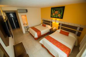 a hotel room with two beds and a television at Hotel Tulija Palenque in Palenque