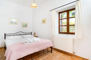 a bedroom with a bed with a pink blanket and a window at Villa Nina in Panagia