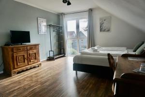 Schlafzimmer mit einem Bett, einem TV und einem Tisch in der Unterkunft Landhotel Strandallee in Wunstorf