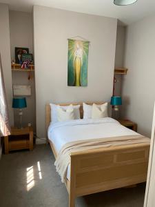 ein Schlafzimmer mit einem Bett und einem Gemälde an der Wand in der Unterkunft Morning Sun Apartment Glastonbury in Glastonbury