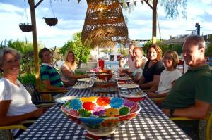 un grupo de personas sentadas alrededor de una mesa larga en B&B Finca Alegria de la Vida en Pizarra