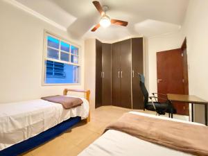 a bedroom with two beds and a ceiling fan at Canal 5 Embaré a 500 m da Praia in Santos