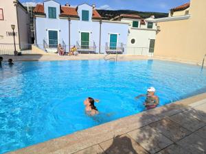 two people are swimming in a swimming pool at Apartman Bruna in Cres
