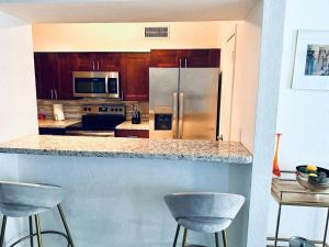 a kitchen with a stainless steel refrigerator and two bar stools at New Star Suite One in North Miami Beach