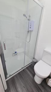 a white bathroom with a shower and a toilet at Haven Cottage - adjacent to beach and promenade in Walmer
