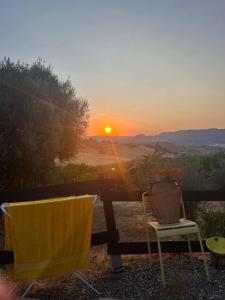 a sunset with a table and chairs and a vase at Glamping Bed and Breakfast Finca Alegria de la Vida in Pizarra