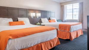 Habitación de hotel con 2 camas con sábanas de color naranja en Knights Inn North Bay, en North Bay