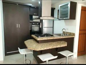 a kitchen with a stove and a sink and some chairs at Confortable apartamento en Marina del Rey Lecheria in El Morro de Barcelona