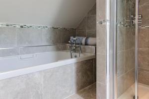 La salle de bains est pourvue d'une baignoire et d'une douche. dans l'établissement Honeysuckle Cottage, à Renvyle
