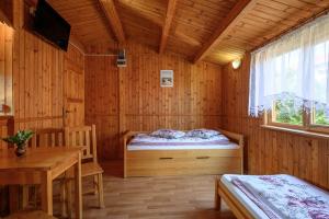 a wooden room with a bed and a table and a window at Domki AGA nad morzem in Bobolin