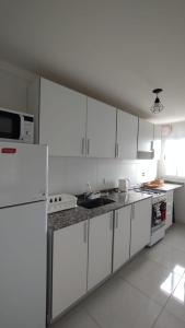 La cuisine est équipée de placards blancs et d'un réfrigérateur blanc. dans l'établissement Departamento amoblado alquiler temporario, à Río Cuarto