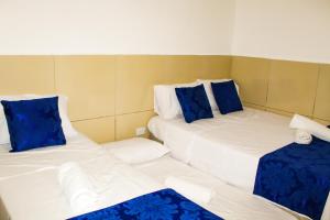 two beds in a room with blue and white pillows at Pousada Farol do Porto in Porto De Galinhas