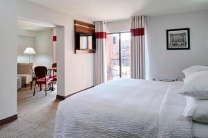 a hotel room with a bed and a dining room at Four Points by Sheraton Detroit Novi in Novi