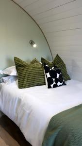 a bed with green and white pillows on it at The Garden Pod with Private Hot Tub in Ballymagan