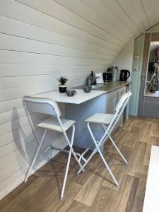 a small kitchen with two chairs and a counter at The Garden Pod with Private Hot Tub in Ballymagan